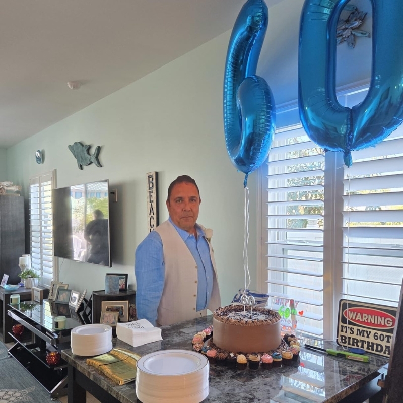 60th birthday party with life-size cutout, chocolate cake and blue number balloons