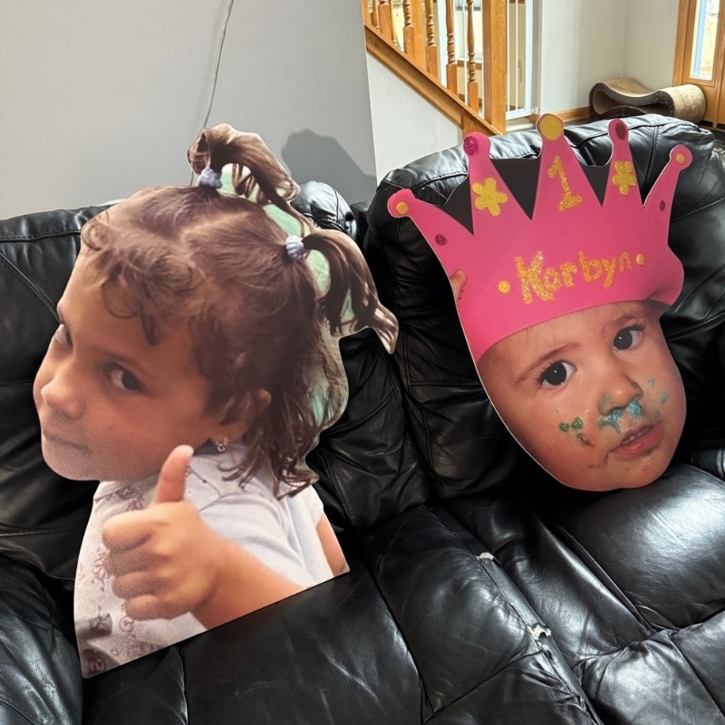 First birthday party with baby big head cutout wearing a crown on couch