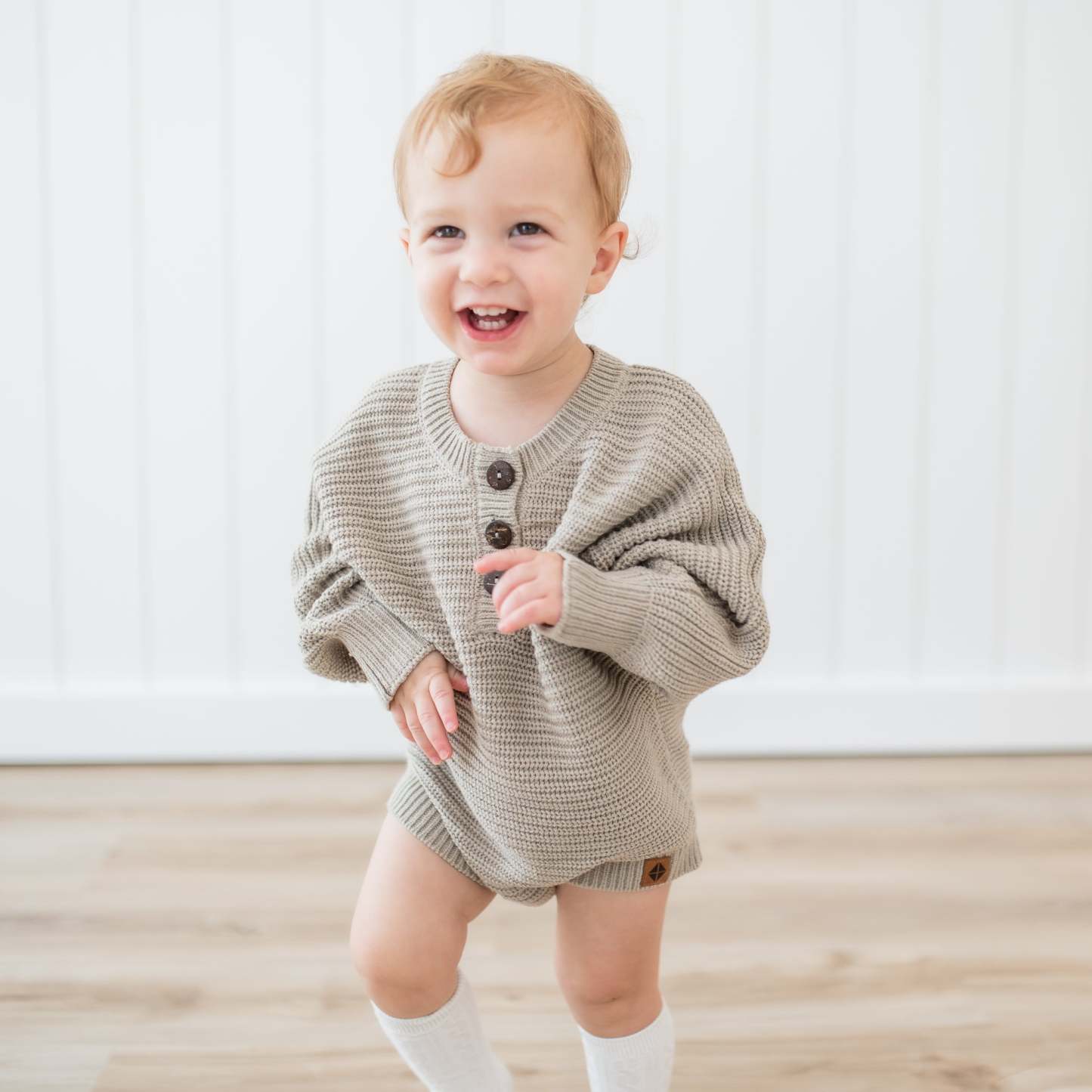 Smiling toddler wearing the Chunky Knit Romper in Almond