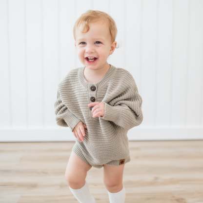 Smiling toddler wearing the Chunky Knit Romper in Almond