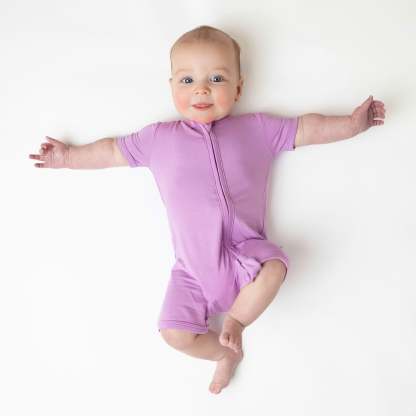 Infant wearing Kyte Baby Zippered Shortall Romper with dual zipper in Poi pink