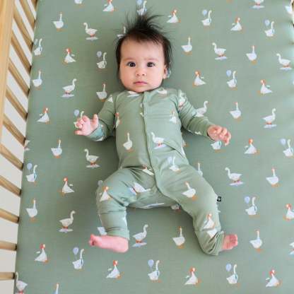 Infant laying in a crib on a Silly Goose Crib Sheet wearing matching snap Romper pajamas