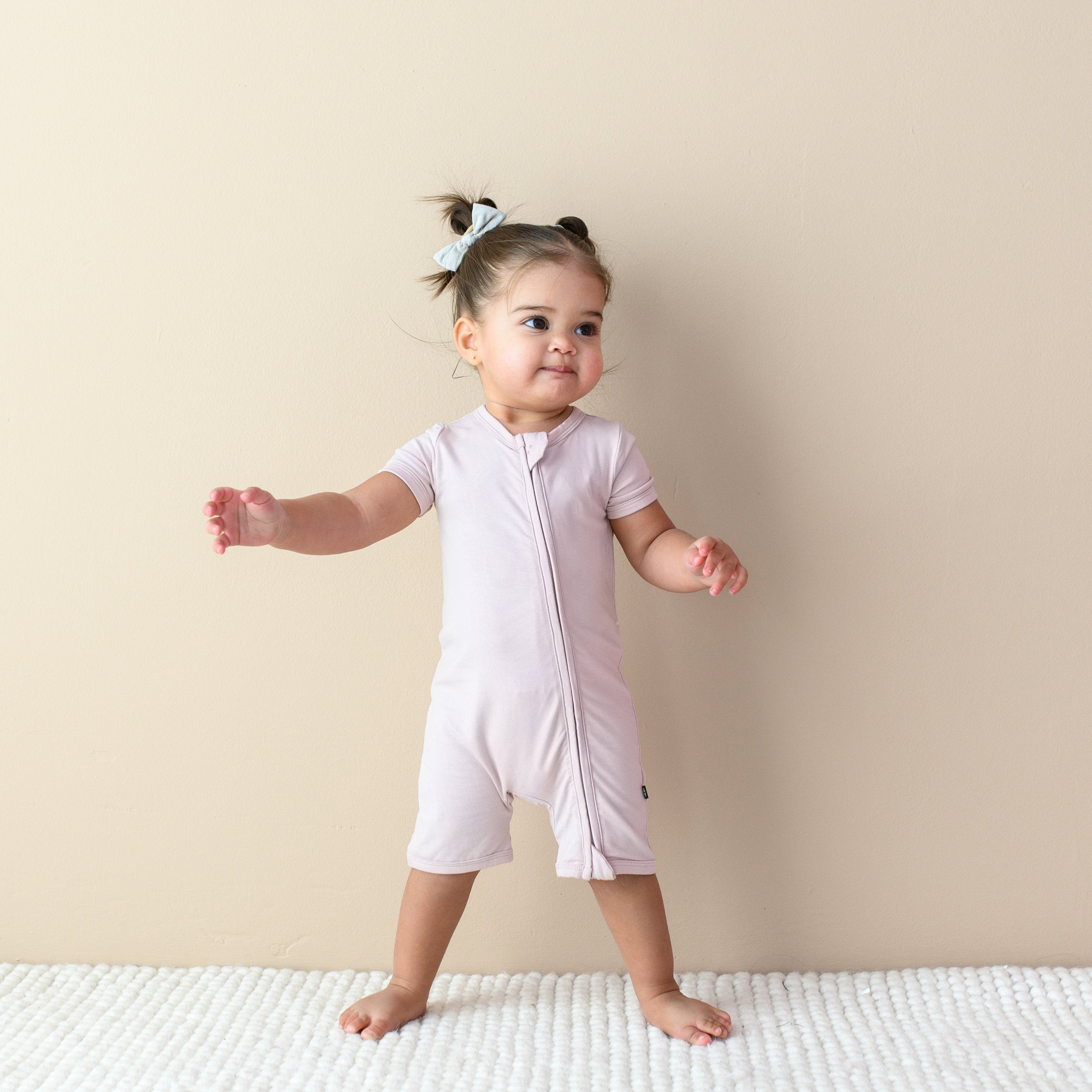 Toddler wearing Kyte Baby Zipper Shortall Romper in Blush