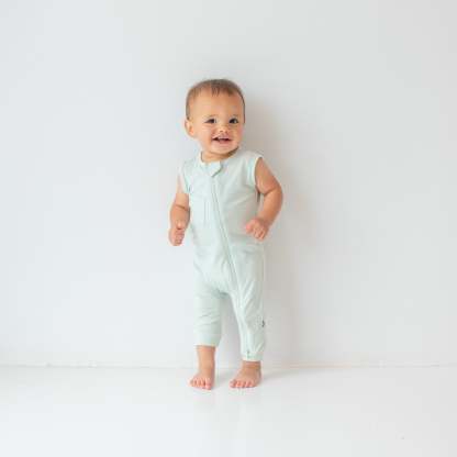 Smiling toddler wearing the Zippered Sleeveless Romper in Dew