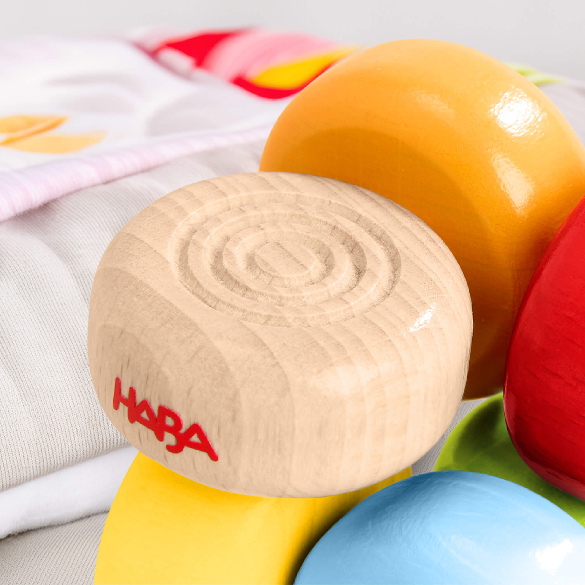 HABA Color Drops Wooden Grasping and Teething Toy on a soft fabric background.