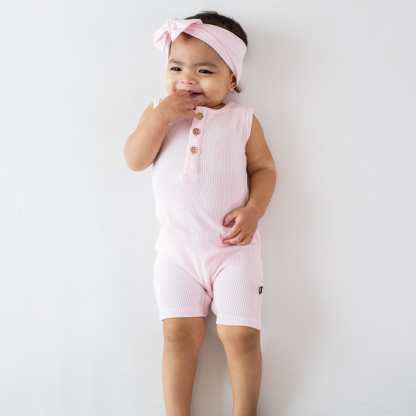 Infant wearing Kyte Baby Ribbed Sleeveless Shortall with wooden buttons in Sakura