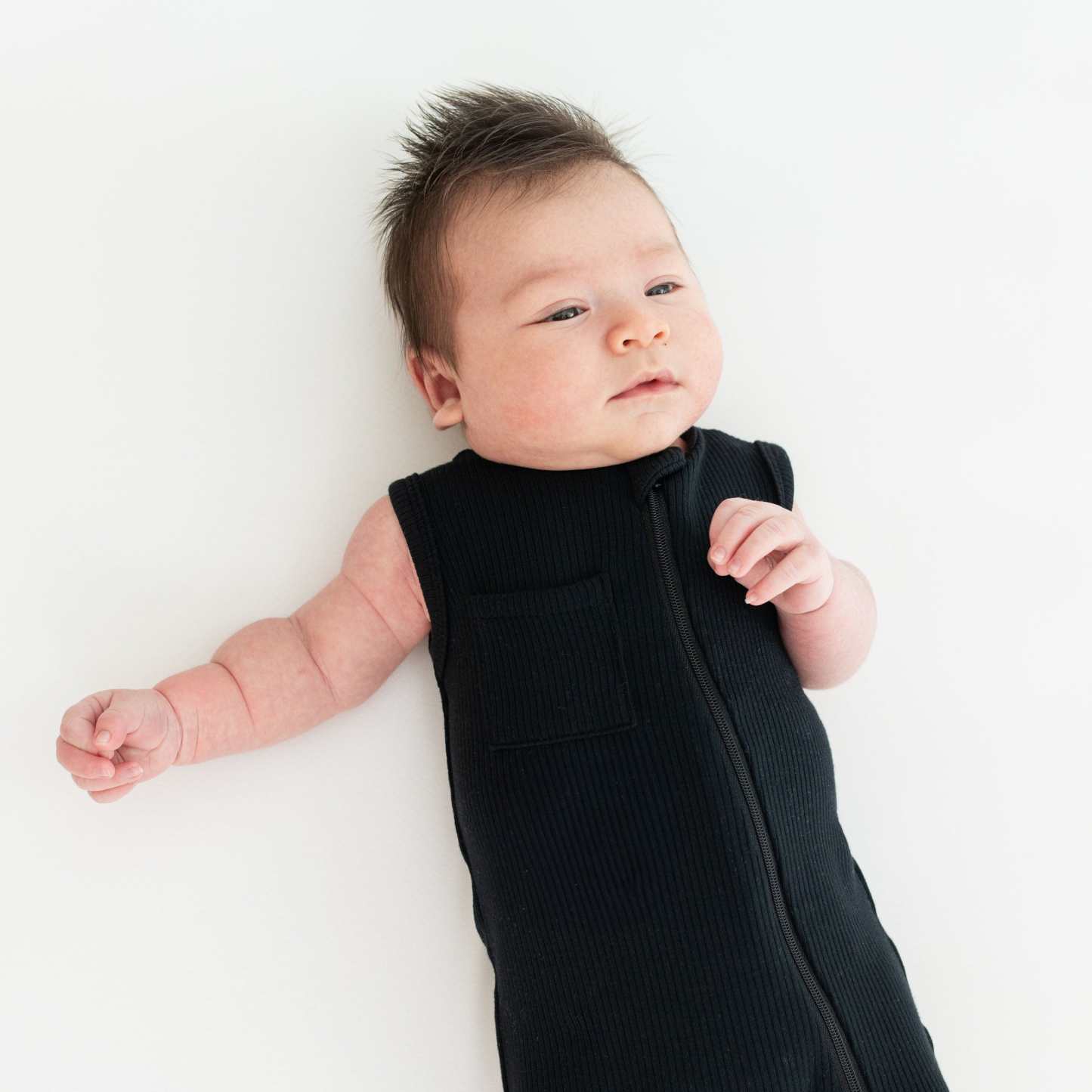 Baby wearing Kyte Baby Sleeveless Zippered Romper in Midnight black