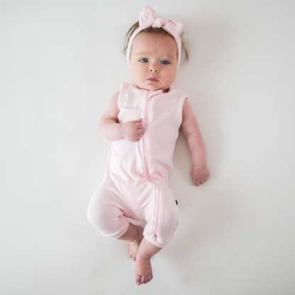 Newborn wearing Kyte Baby bamboo Ribbed Zippered Sleeveless Romper in Sakura pink