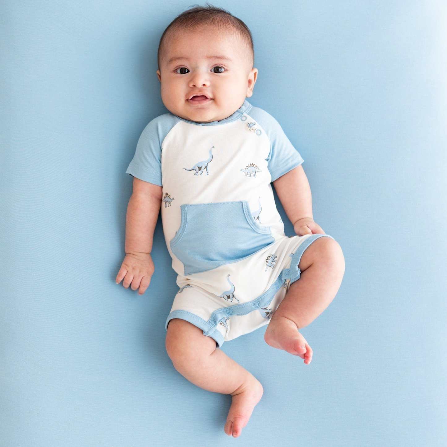 Infant wearing Kyte Baby Shortall in Jurassic