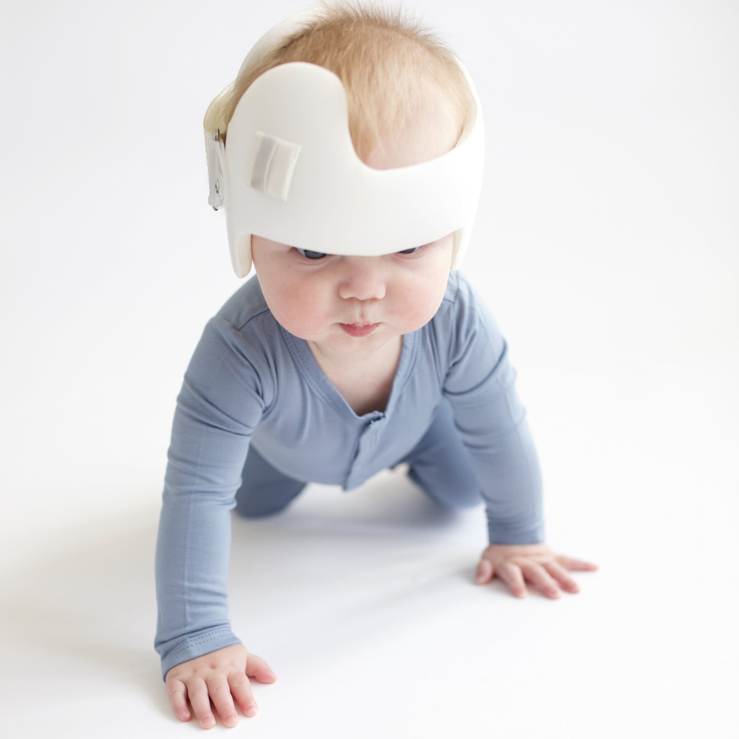 Baby crawling in white room while wearing a Kyte Baby Snap Romper Romper in Slate