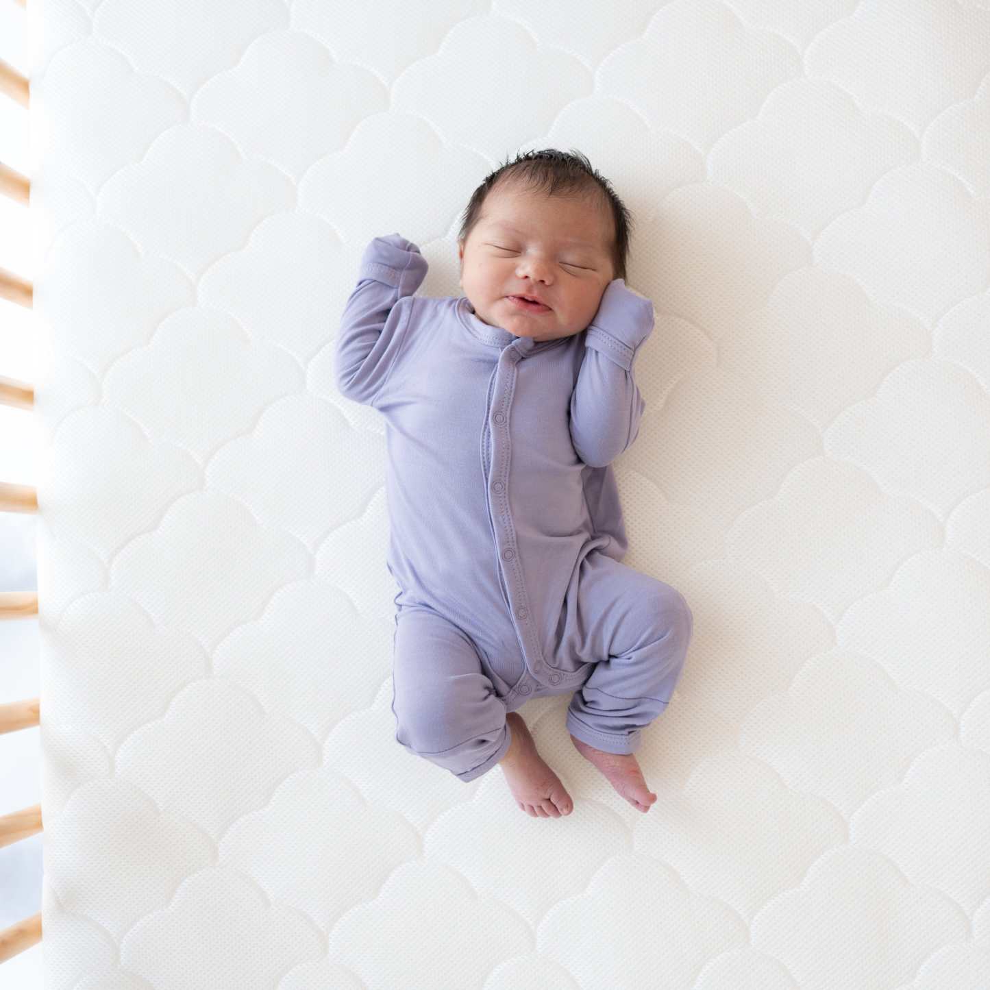 Newborn wearing long sleeve Kyte Baby Romper with snaps in Taro