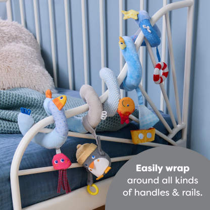 Penguin Activity Spiral Stroller & Car Seat Toy on a bed rail, text reads 'Easily wrap around all kinds of handles and rails'