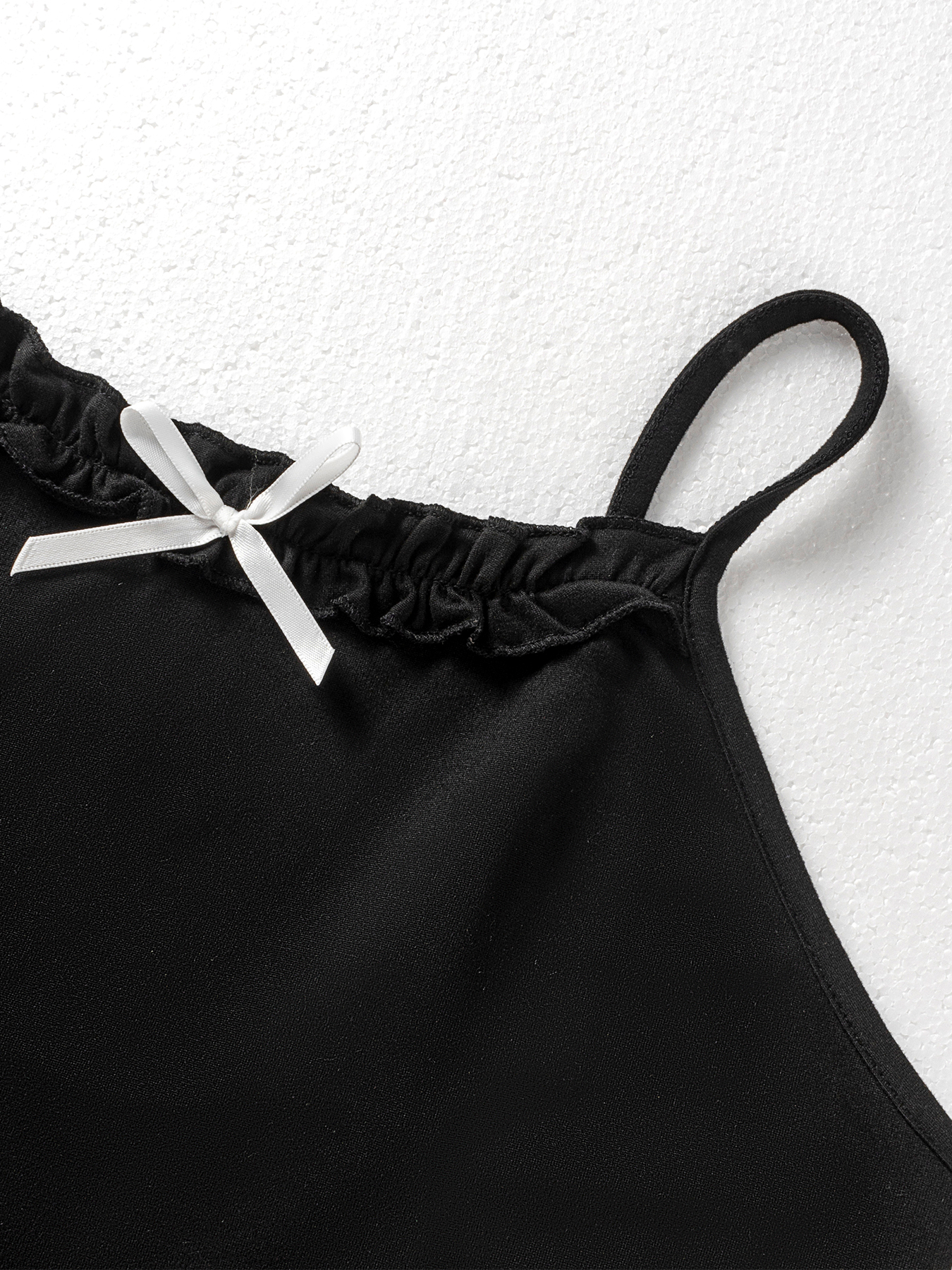 Woman's Black spaghetti strap mini dress with ruffled neckline and bow embellishment.