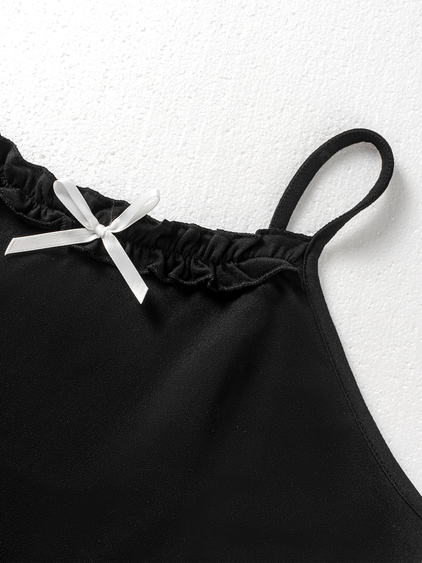 Woman's Black spaghetti strap mini dress with ruffled neckline and bow embellishment.