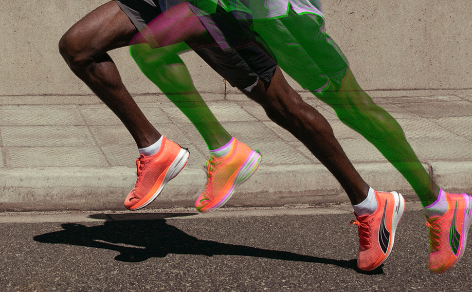 Athletic shot showing bright coral-colored running shoes in motion against concrete background, capturing dynamic running stance