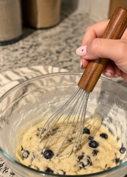 Wood-handled whisk in blueberry batter