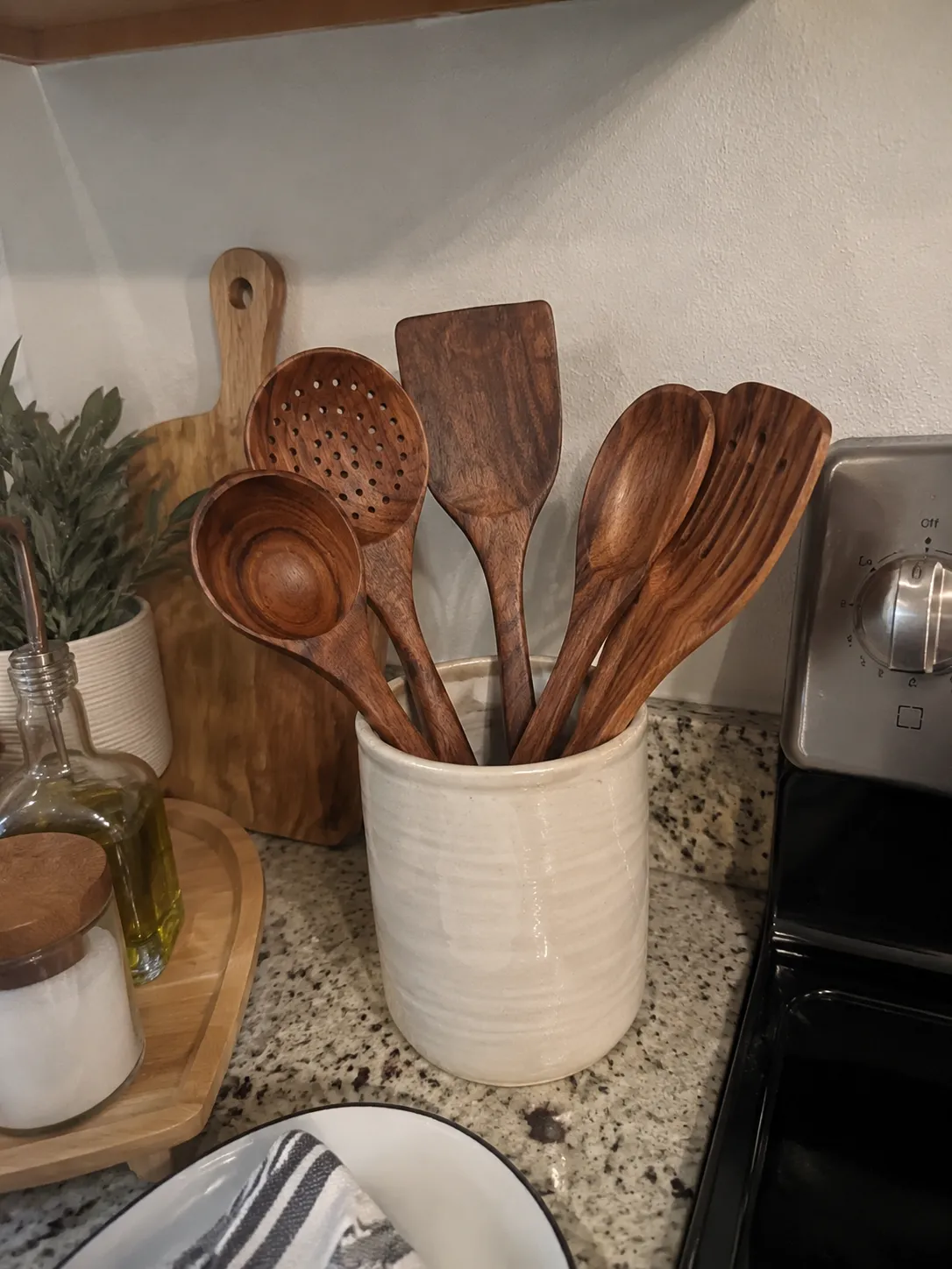 Wood utensils in a ceramic pot beside a stove