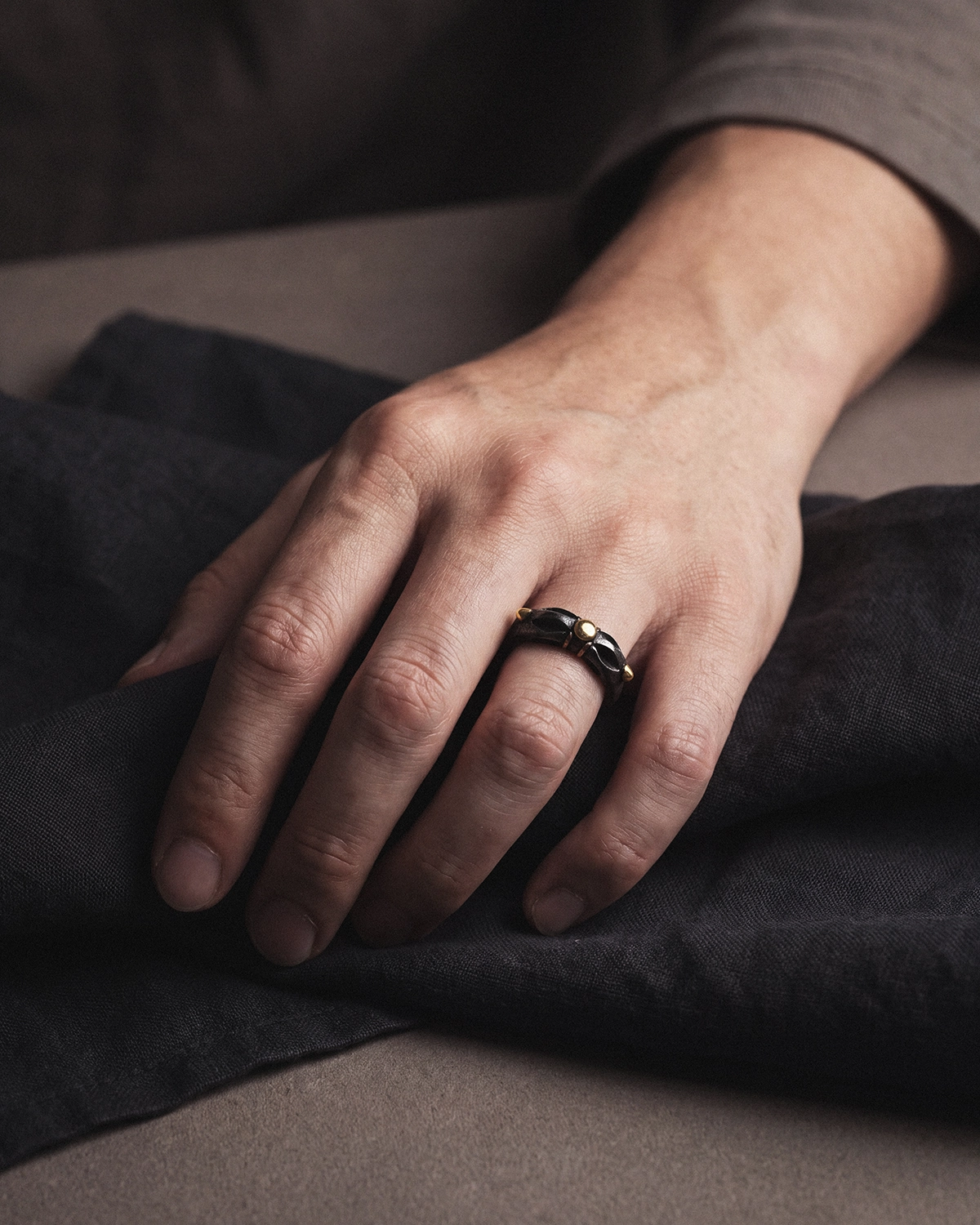 Cold Iron Vajra Dorje ring worn on a hand resting on dark textile.