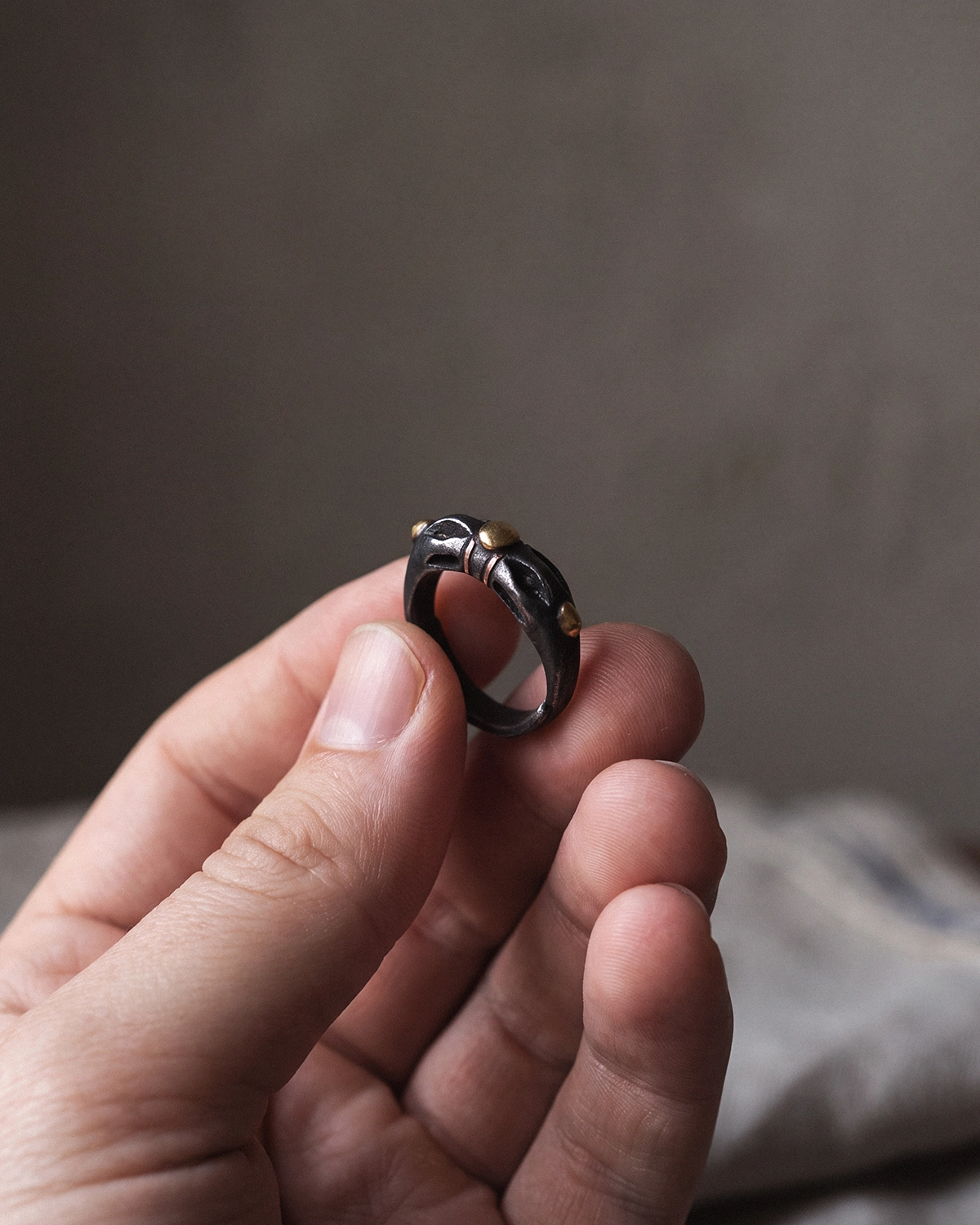 Cold Iron Vajra Dorje ring held between fingertips to show its compact scale and dark metal texture.