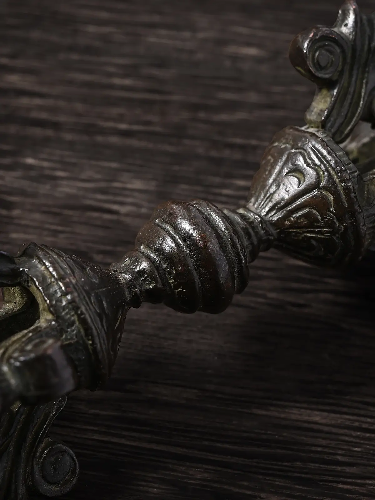 Close up detail of the engraved ribbed central shaft of a copper vajra, a traditional Tibetan Buddhist symbol