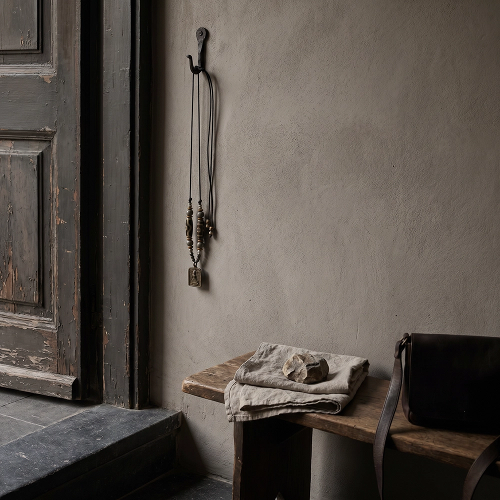 {"default":"Square mobile banner showing a Tibetan-inspired hanging charm beside an aged doorway with dark wood, linen, stone, and restrained entryway styling."}
