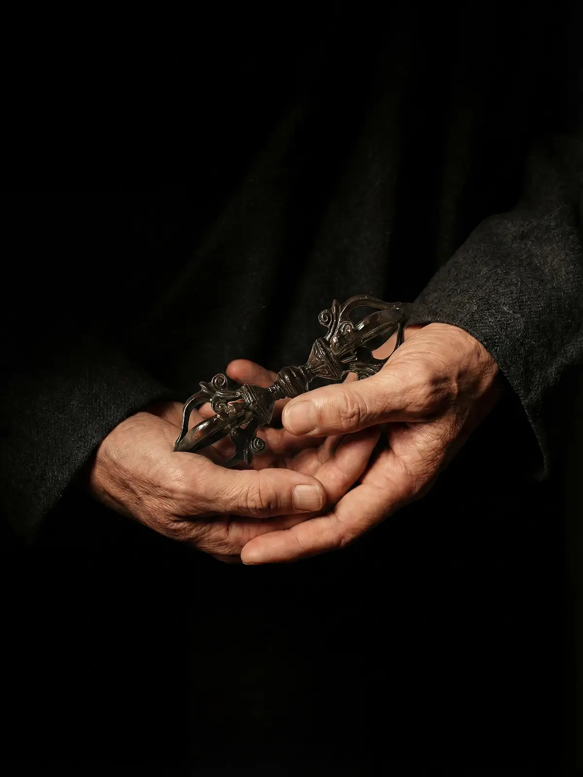Substantial aged copper Tibetan four-pronged dorje held gently in the palms of hands for meditation practice