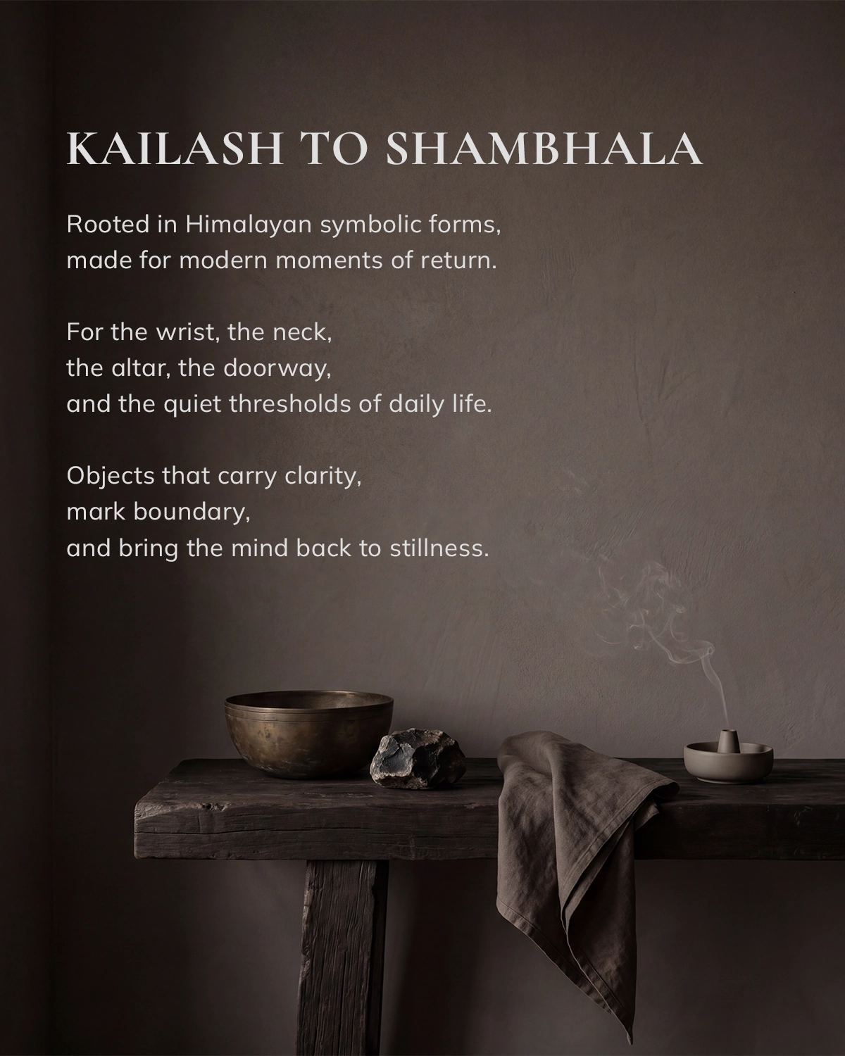 Brand image reading 'KAILASH TO SHAMBHALA' above a dark wooden table with a metal bowl, stone, folded cloth, and a smoking incense holder.