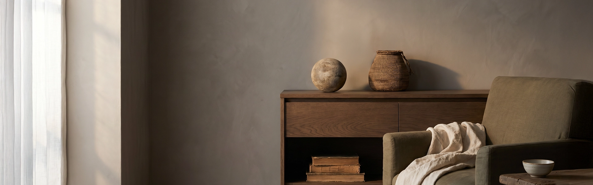 Refined living room scene with warm plaster wall, wooden sideboard, muted sofa, linen throw, ceramic bowl, and quiet symbolic home decor atmosphere.