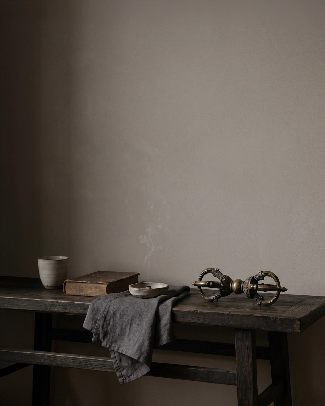 {"default":"Aged bronze Vajra ritual object on a dark wooden table in a quiet wabi-sabi home interior"}
