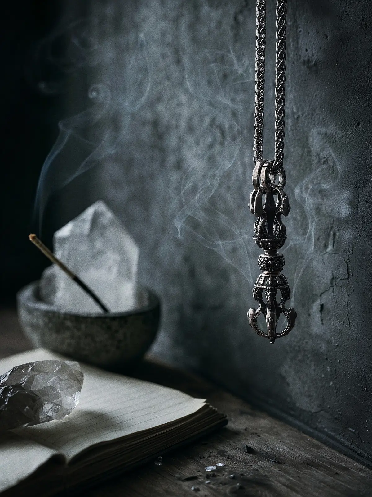 A Rotatable Vajra Pendant suspended near a clear quartz crystal. The spinning motion symbolizes cutting through confusion. Moody spiritual photography for mindfulness and clarity.