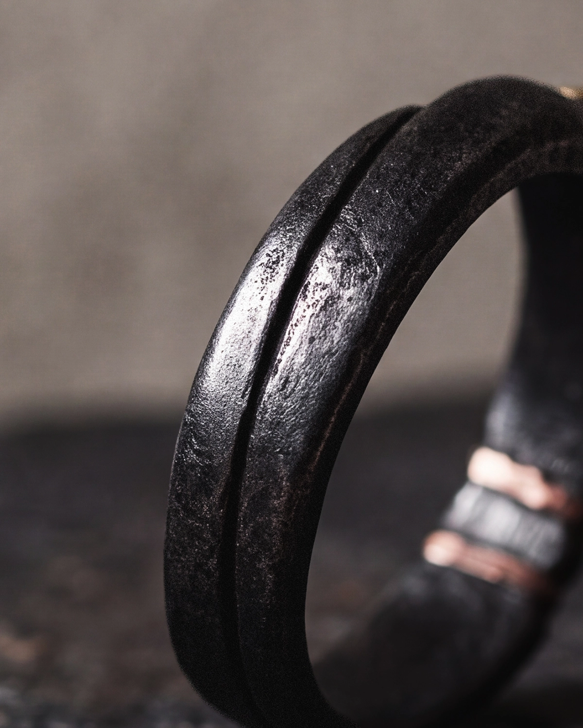 Close-up of a cold iron vajra ring showing the back of the band with a raised ridge and a finely pitted, dark surface.
