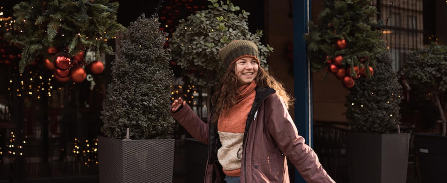 Wintertafereel buiten met versierde groenblijvende bomen in plantenbakken, met kerstverlichting en rode ornamenten