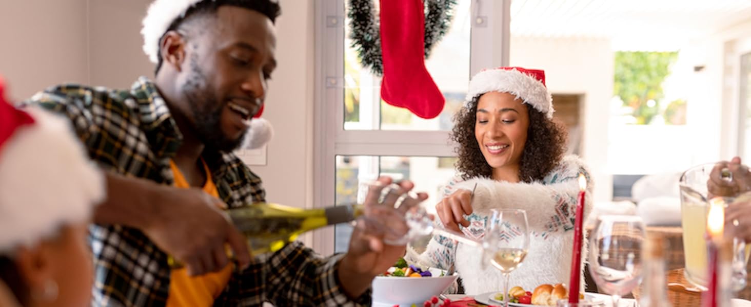 Feestelijke eettafel met kerstversieringen. Mensen genieten van een maaltijd met borden eten, wijnglazen en een rode kous zichtbaar op de achtergrond