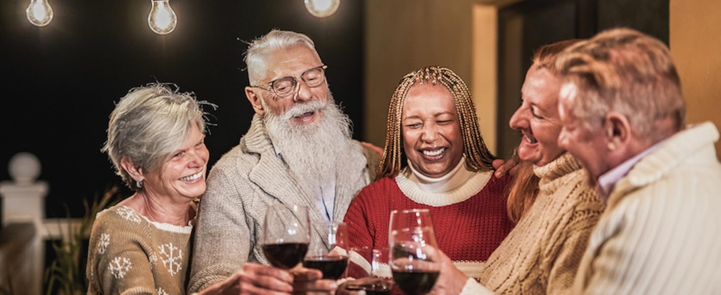 Een groep verschillende mensen die roosteren met wijnglazen onder lichtslingers, wat zorgt voor een warme, feestelijke sfeer