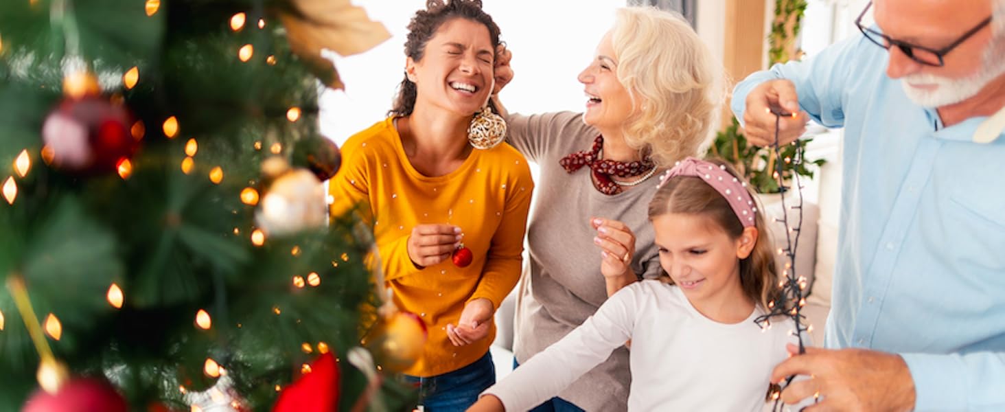 Feestelijke vakantiescène in de buurt van een versierde kerstboom met rode ornamenten, waarop meerdere generaties genieten van hun tijd samen.