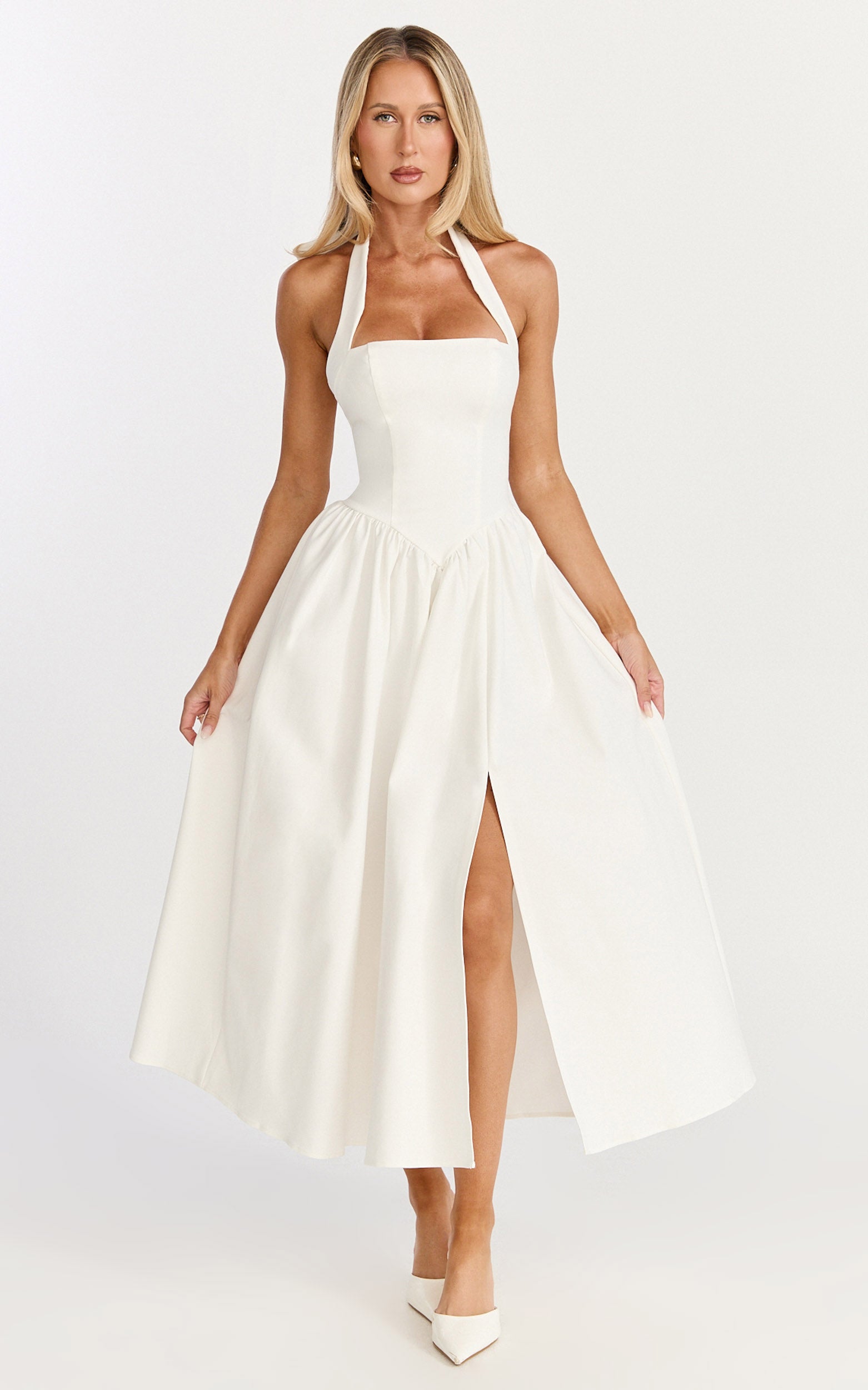 Model is wearing a halter neck, corseted panel midi dress in off white.