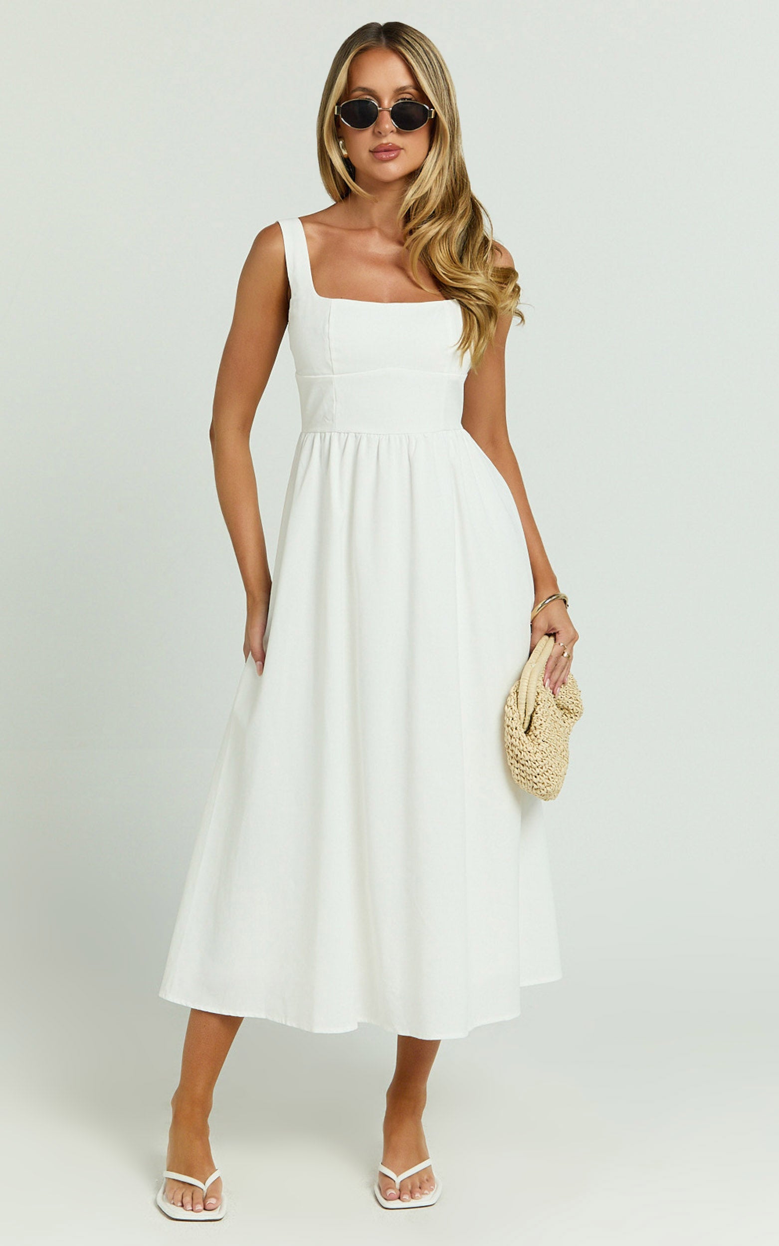 Model is wearing a square neck a-line midi dress in white.