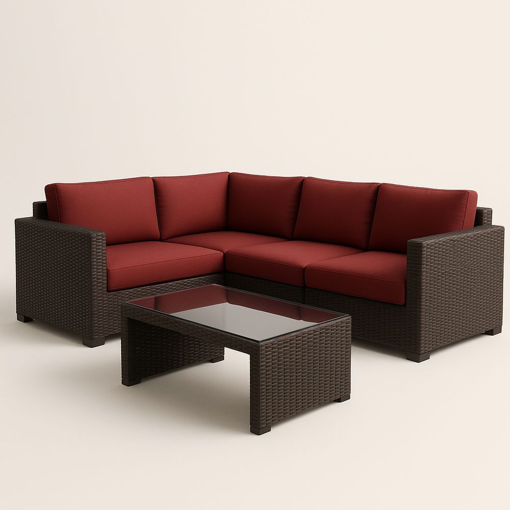 Canapé d'angle en résine tressée avec coussins rouges et table en verre marron