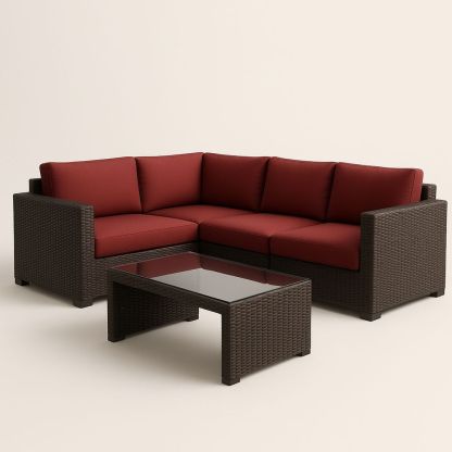 Canapé d'angle en résine tressée avec coussins rouges et table en verre marron