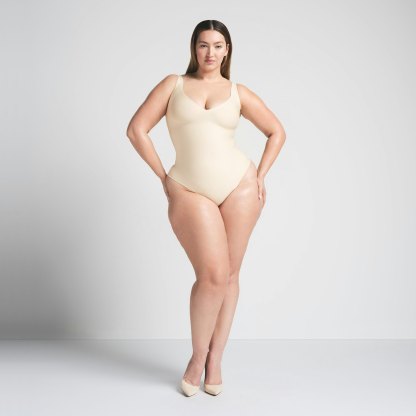 SKIMS BODY UNLINED PLUNGE THONG BODYSUIT - SAND