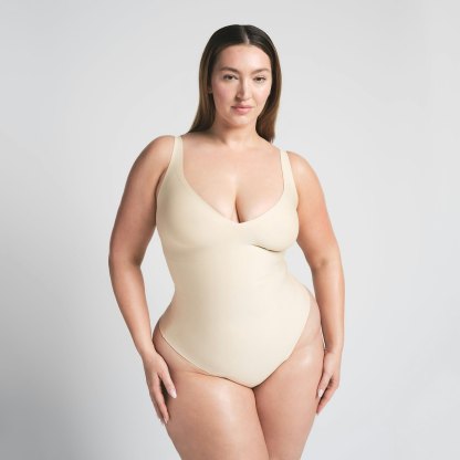 SKIMS BODY UNLINED PLUNGE THONG BODYSUIT - SAND