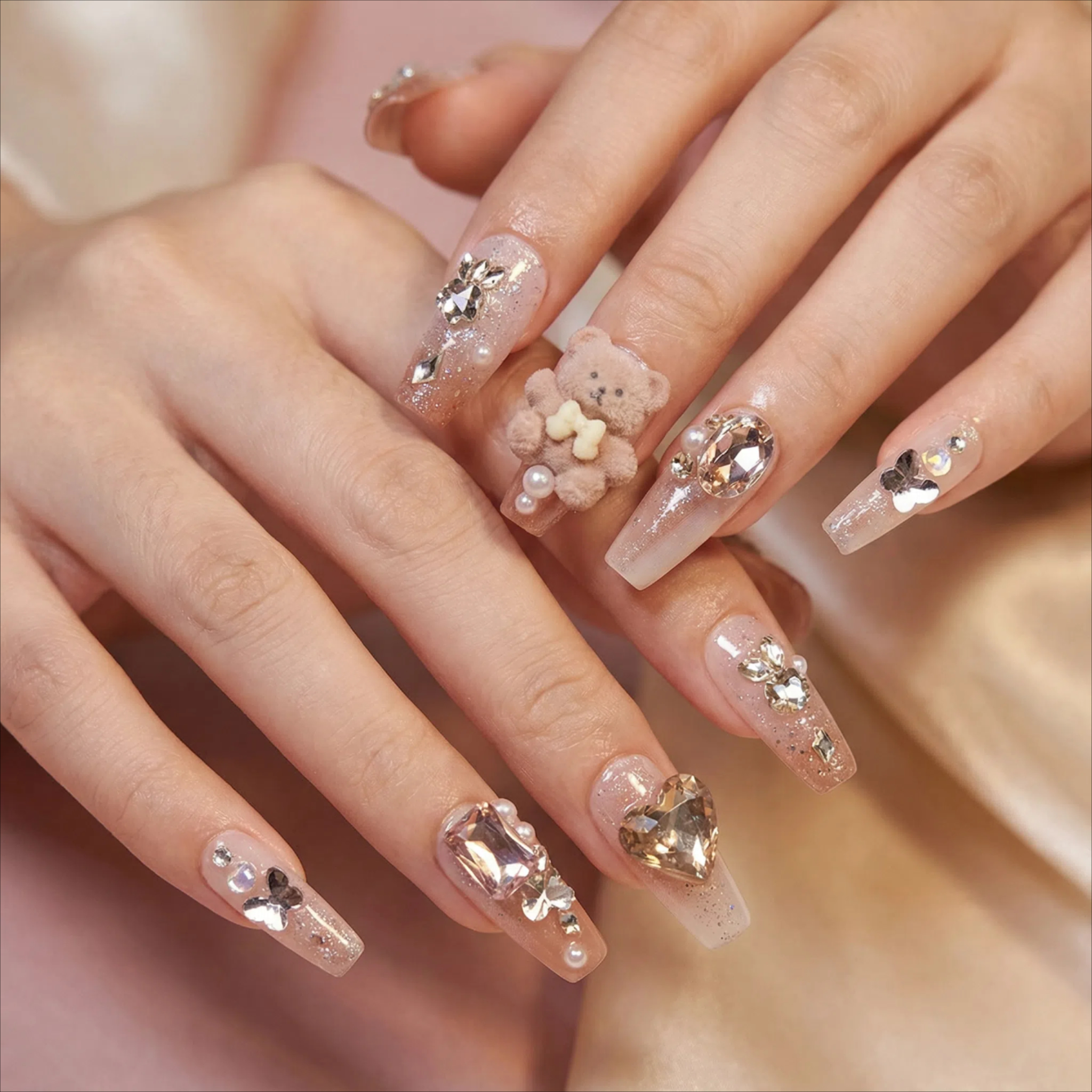 Model wearing champagne nude press on nails with pearls and crystal rhinestones, glossy finish