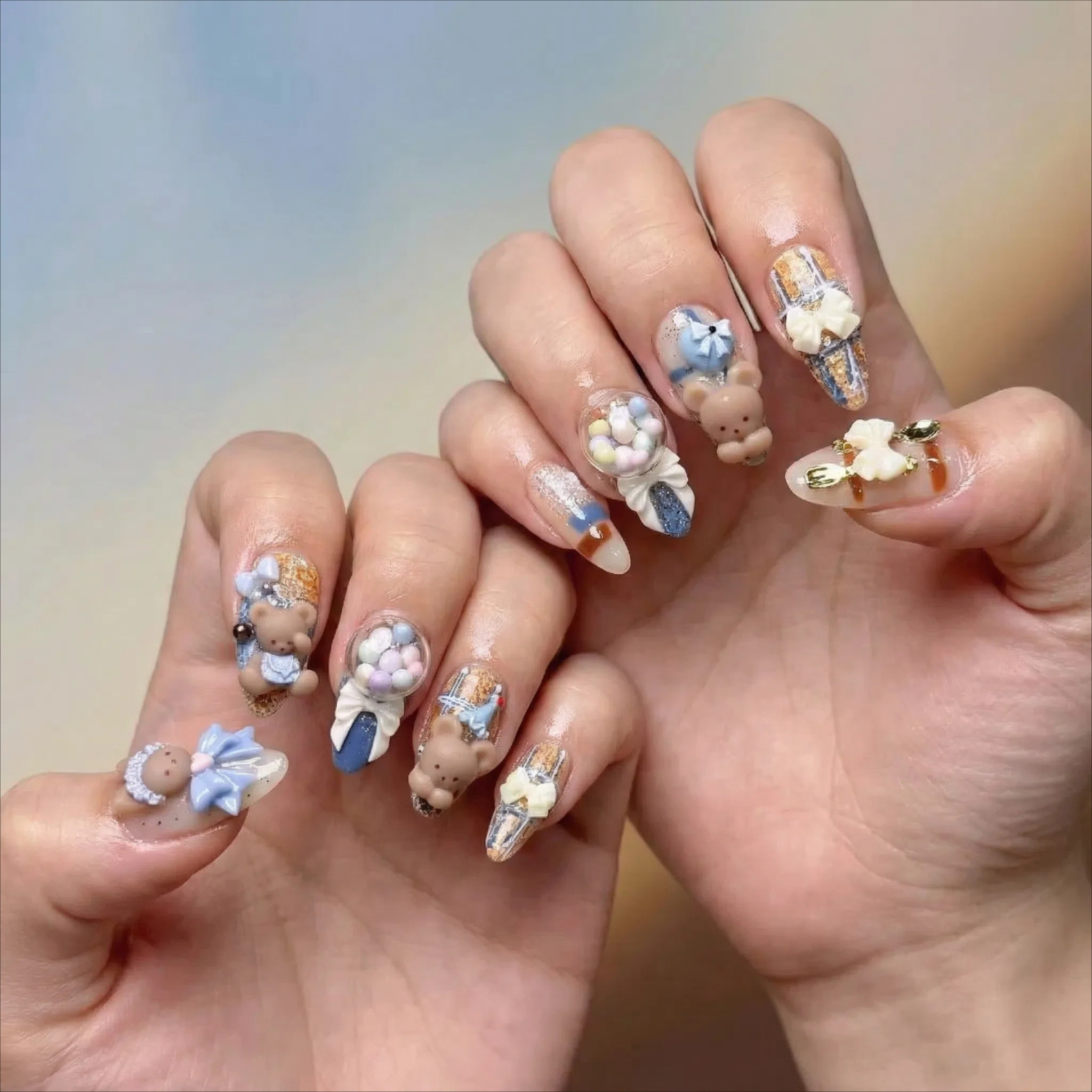 alt="Model wearing blue and nude 3D teddy bear and bunny press on nails with bows and candy details"