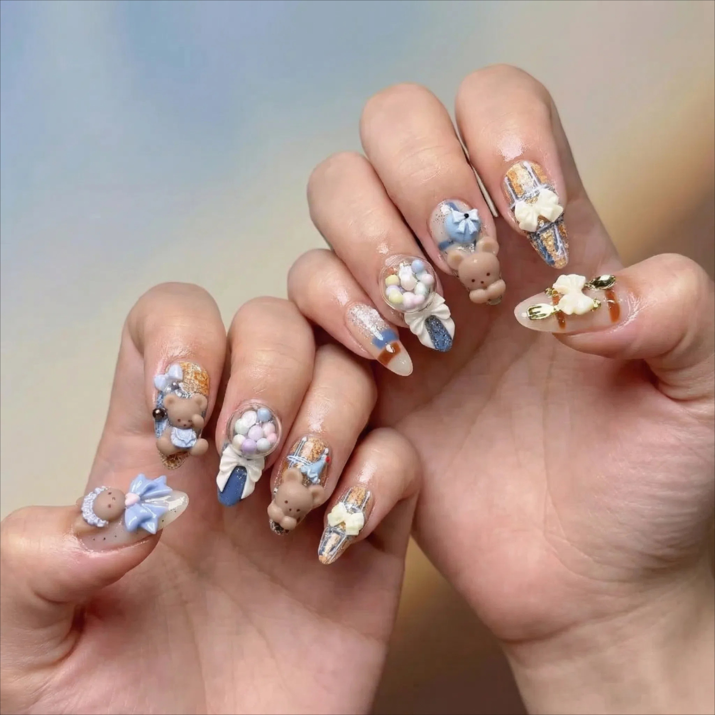alt="Model wearing blue and nude 3D teddy bear and bunny press on nails with bows and candy details"