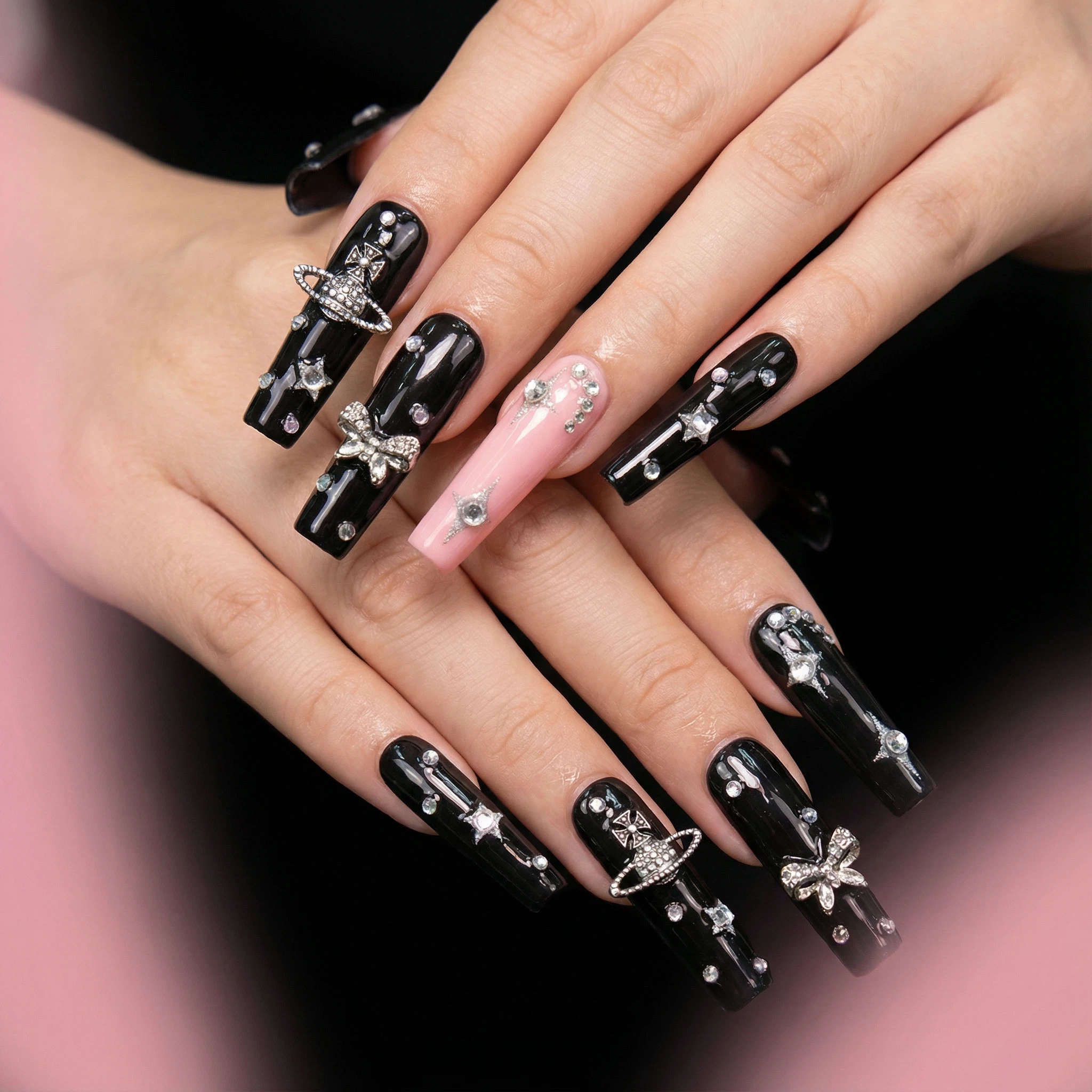 Model wearing black pink cross press-on nails, coffin shape with silver charm and rhinestones close-up