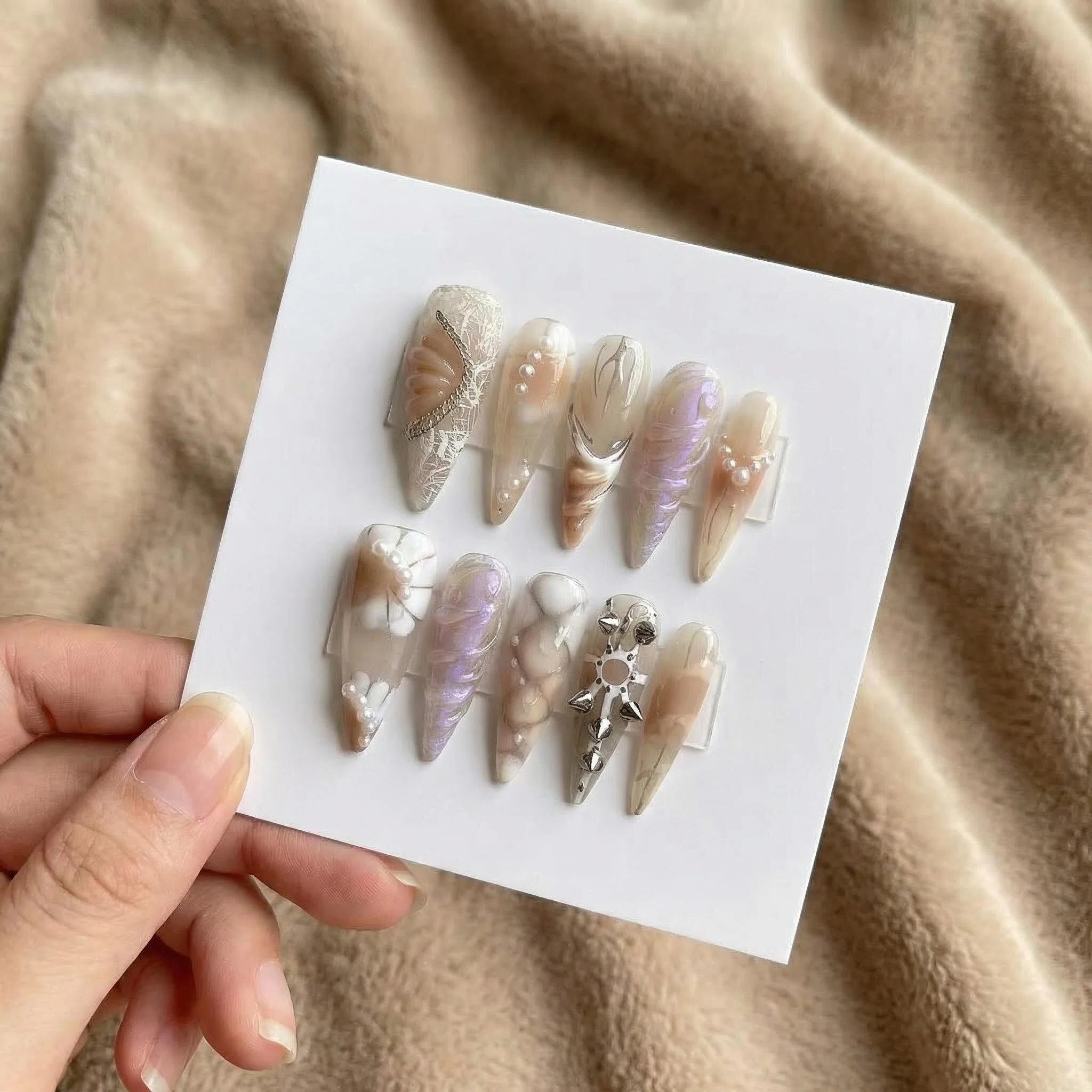 Champagne nude chrome press-on nails set with pearl shine and metallic accents on display card