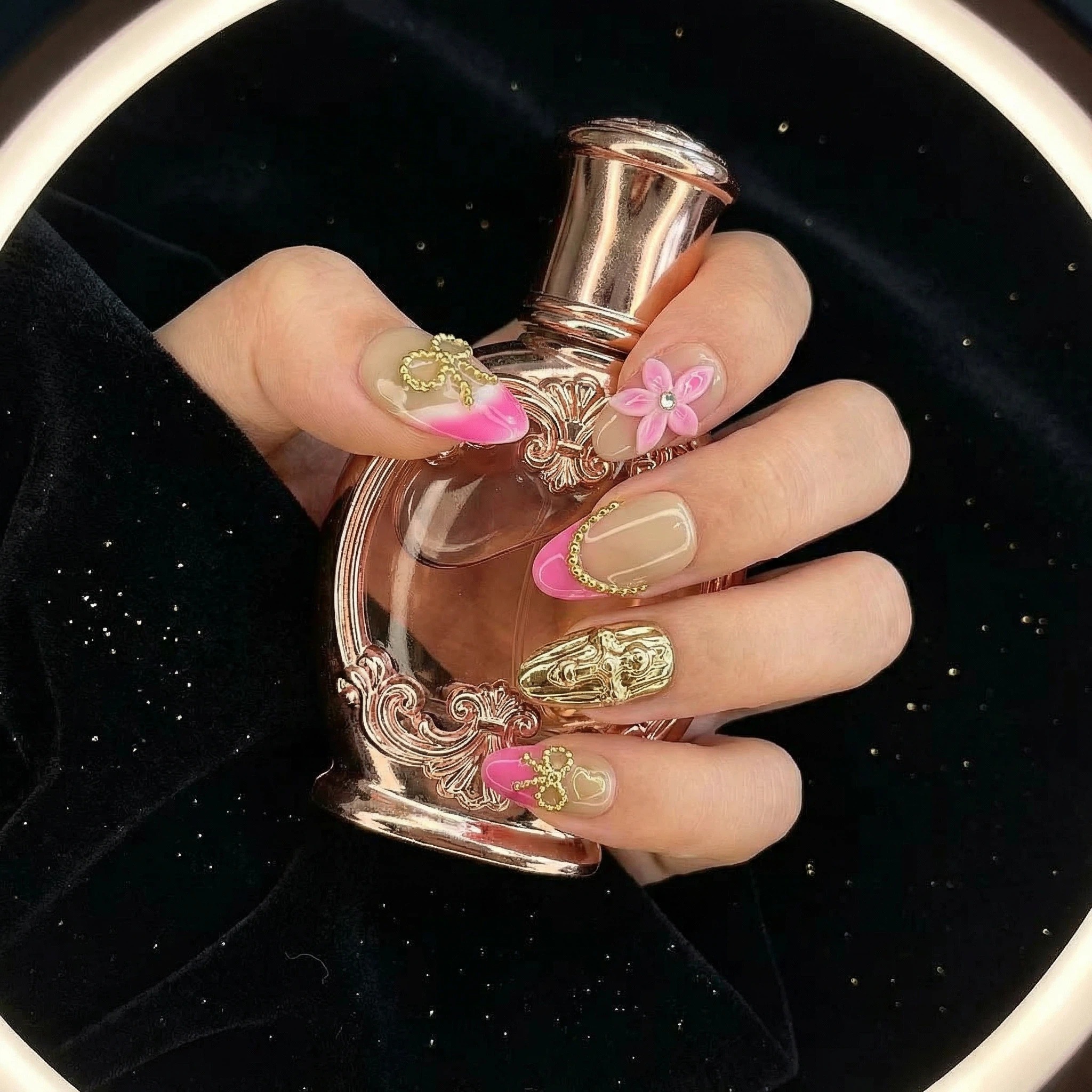 Model holding perfume wearing nude champagne press-on nails with 3D flower and gold details