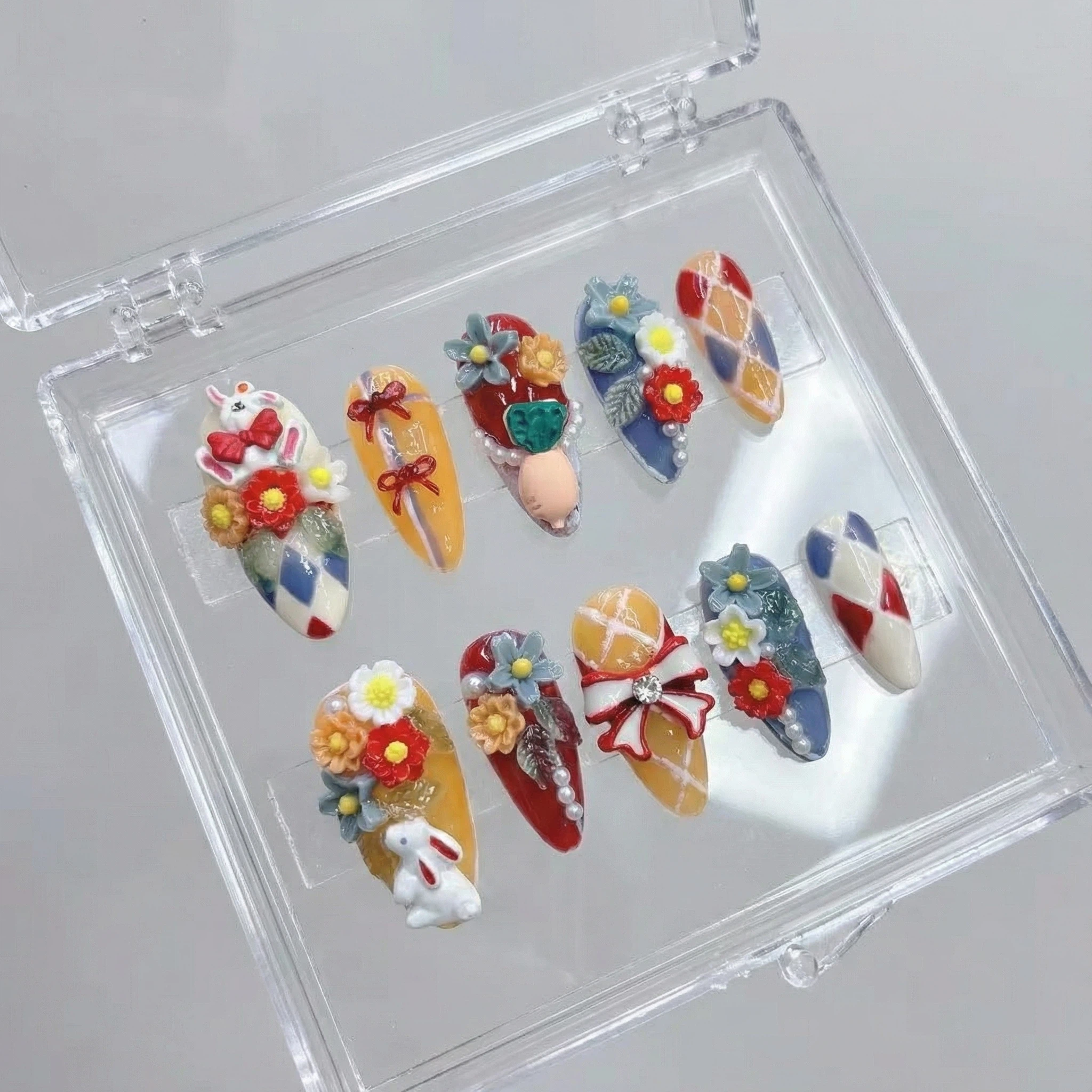 Press-on nails set arranged in a clear storage box with 3D flower and ribbon details