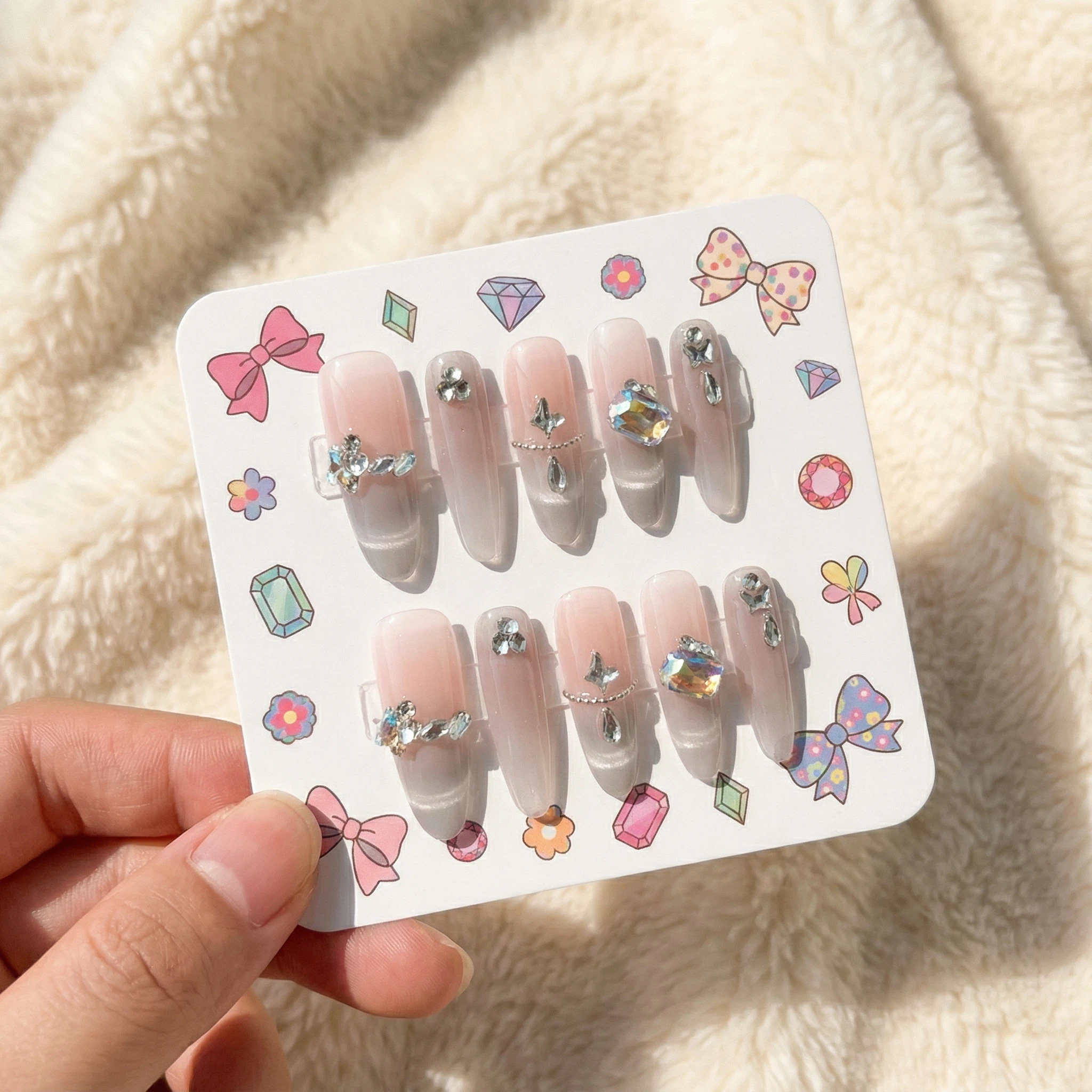 Nude pink silver glitter ombré press-on nails with pearl and crystal accents on display card