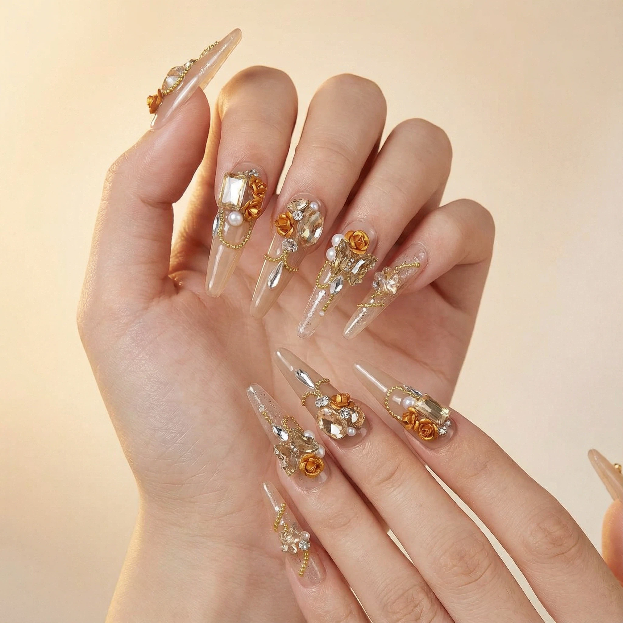 Nude sheer stiletto press on nails with amber gemstone and pearl details on hand, luxury reusable press-ons